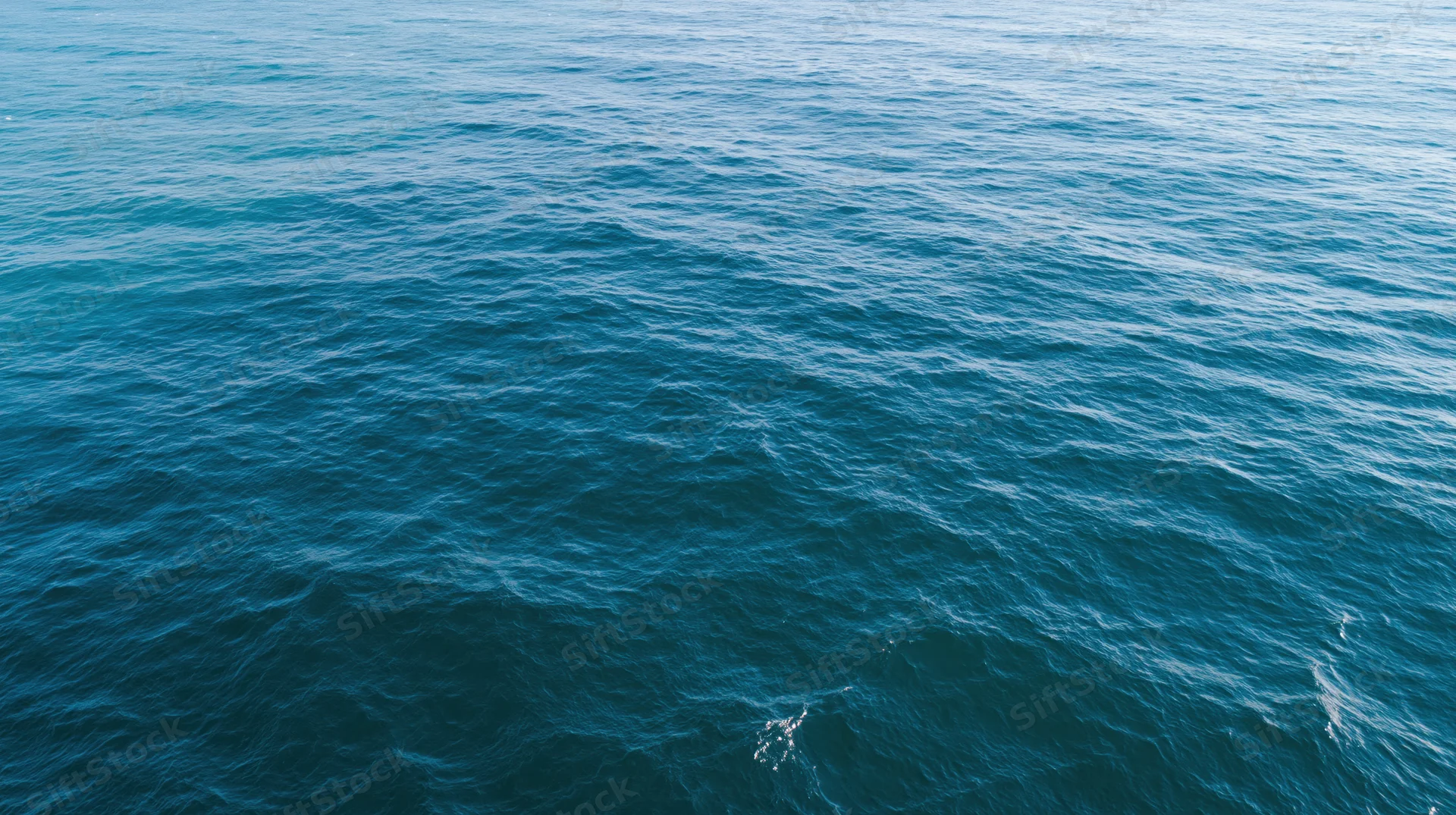 Aerial top-down view of open ocean surface with gentle ripples