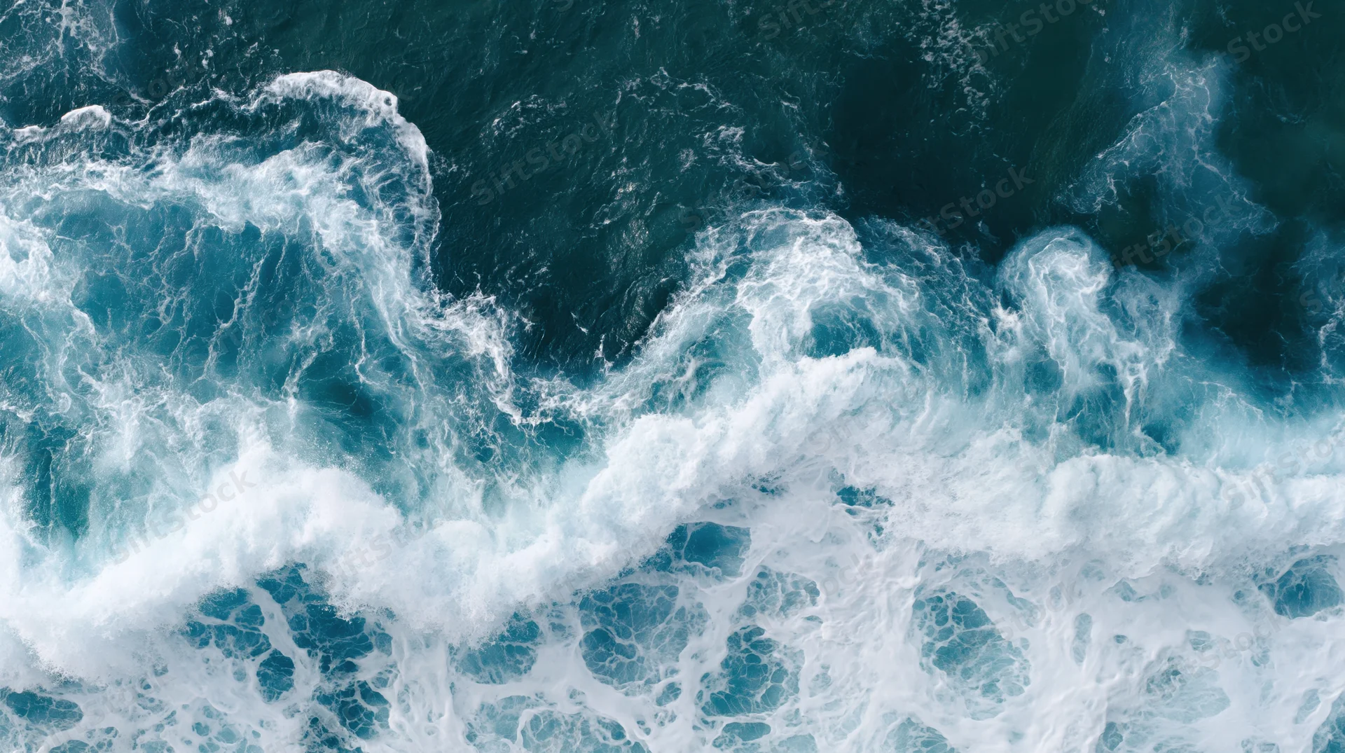 Aerial top-down view of turbulent ocean waves breaking and churning with white foam