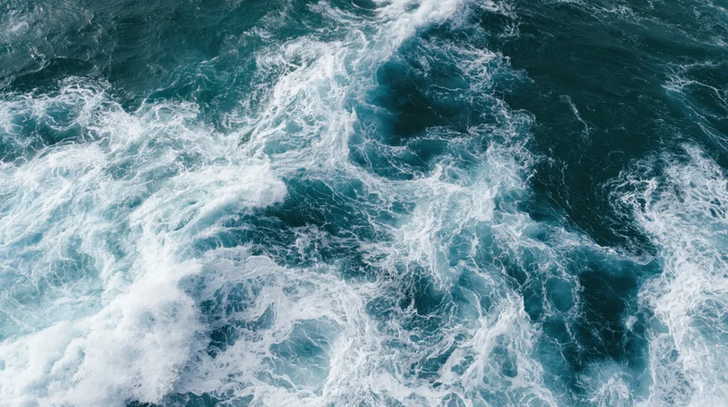 Aerial top-down view of turbulent ocean waves breaking and churning with white foam