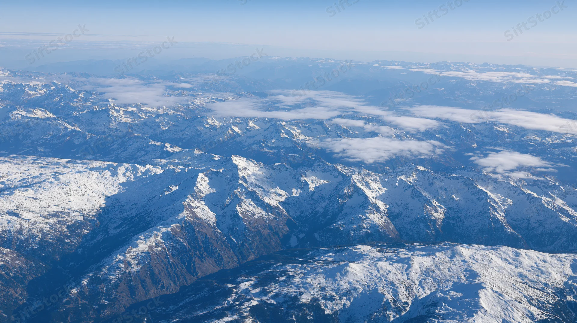 Aerial view of snow-covered mountain range under clear sky