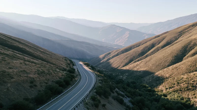 Aerial view of a winding two-lane highway through mountainous terrain