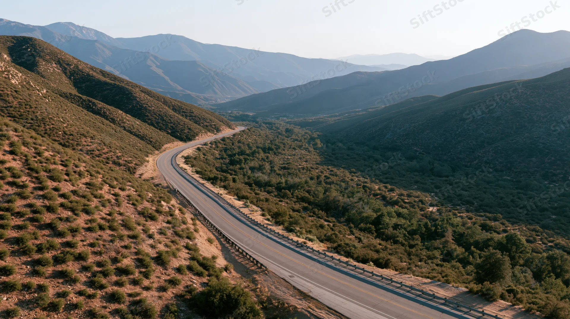 Aerial view of a winding two-lane highway through mountainous terrain