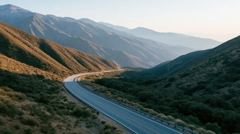 Winding two-lane highway through mountain valley at golden hour