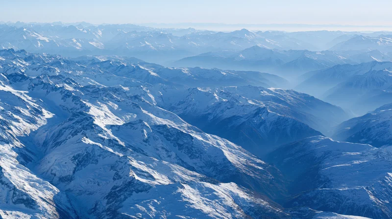 Aerial view of vast snow-covered mountain range stretching to the horizon
