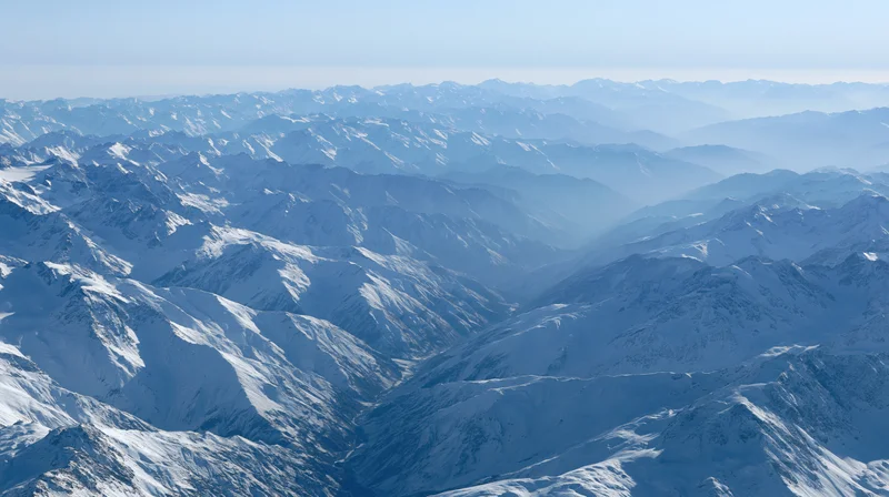 Aerial view of vast snow-covered mountain range stretching to the horizon