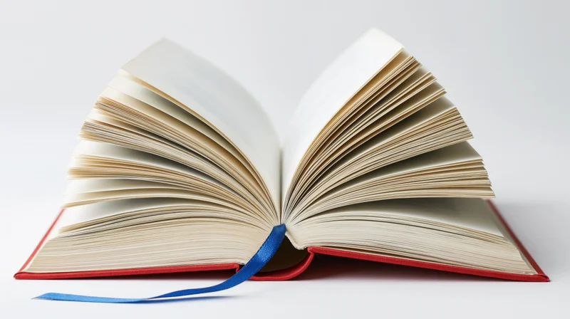 Open hardcover book with pages fanned wide and blue ribbon bookmark on white background