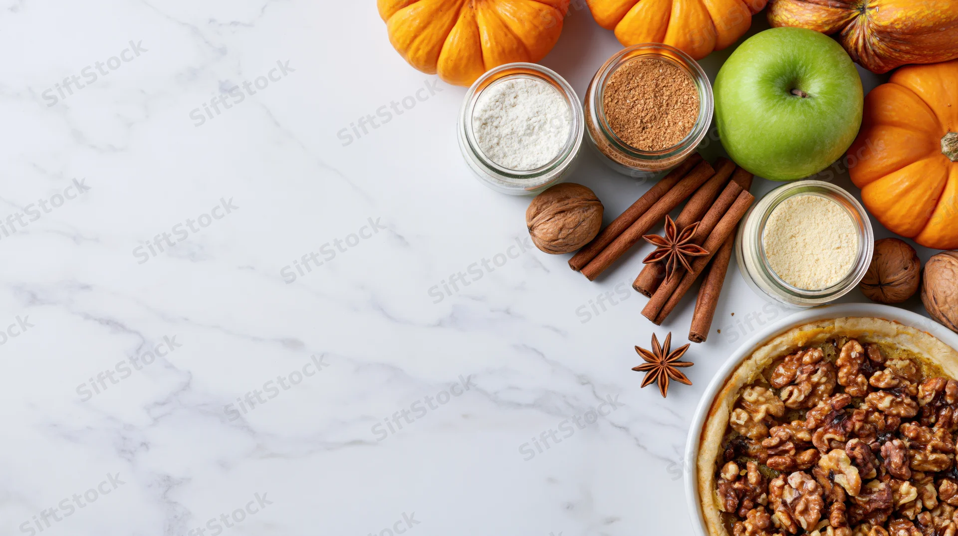 Autumn baking flatlay with pumpkins, spices, apples and walnut pie on marble countertop