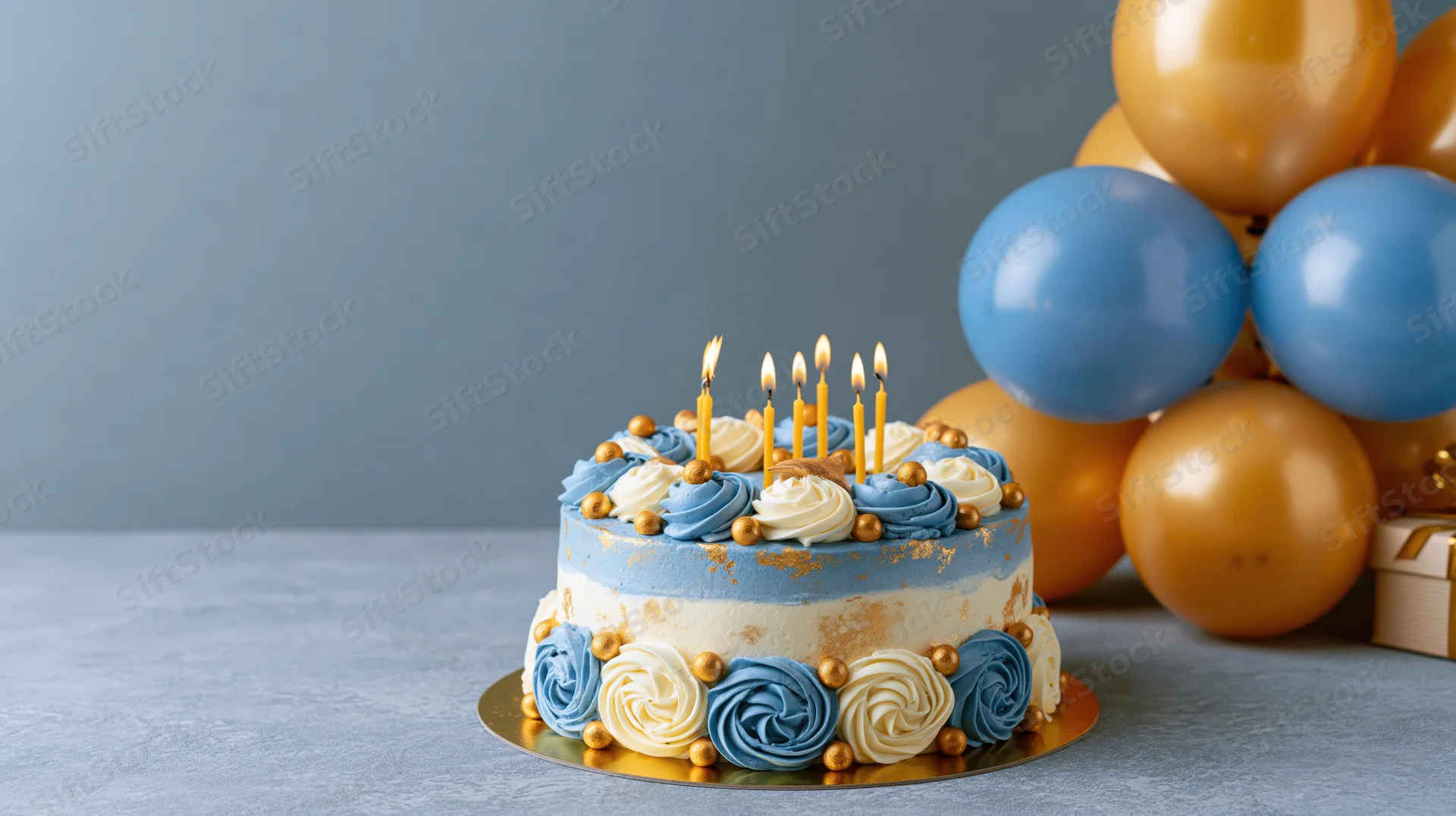 Birthday cake with lit candles and blue gold balloons on a table