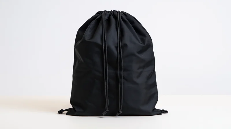 Black drawstring backpack standing upright on white surface