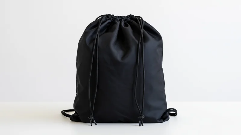 Black drawstring backpack standing upright on white surface