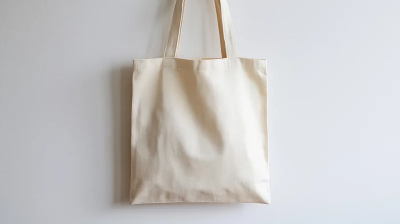 Blank natural canvas tote bag hanging upright against a white background