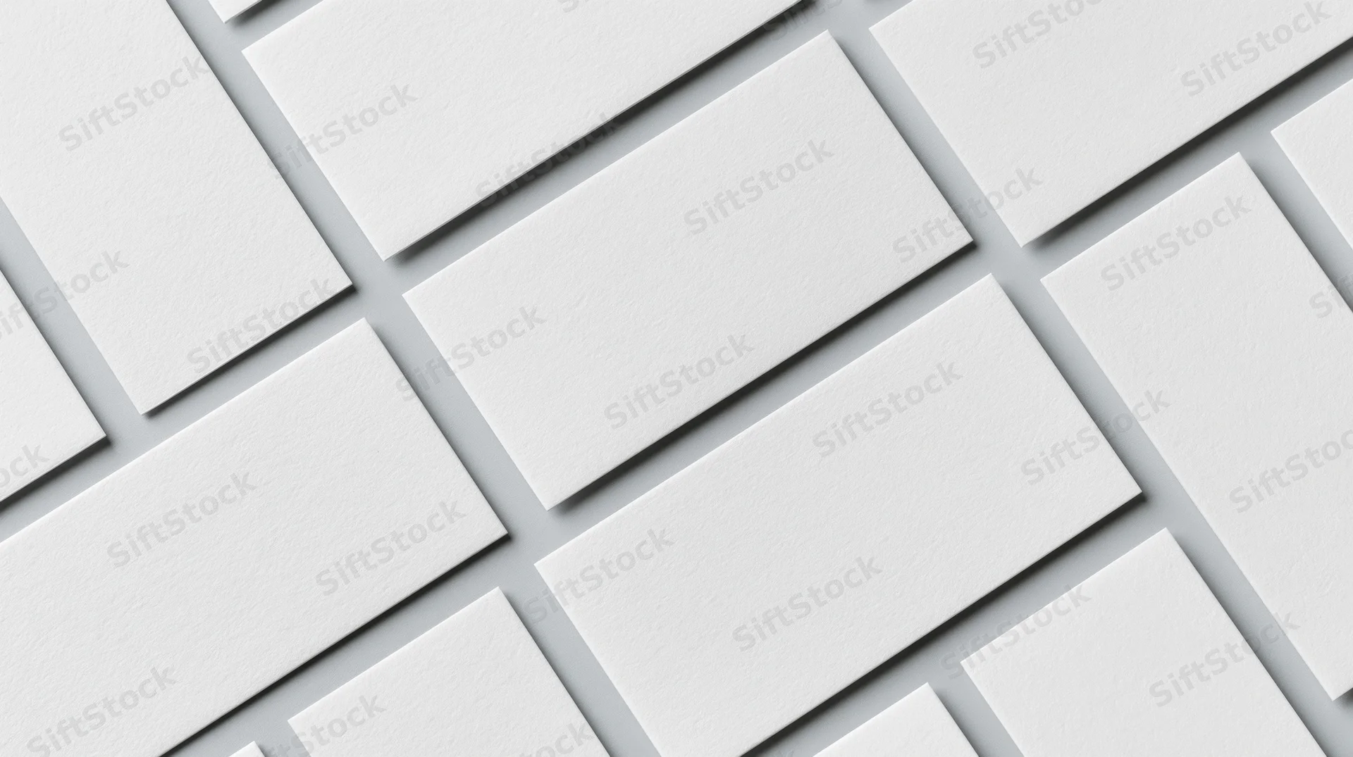 Blank white business cards arranged diagonally in a repeating pattern on a flat surface