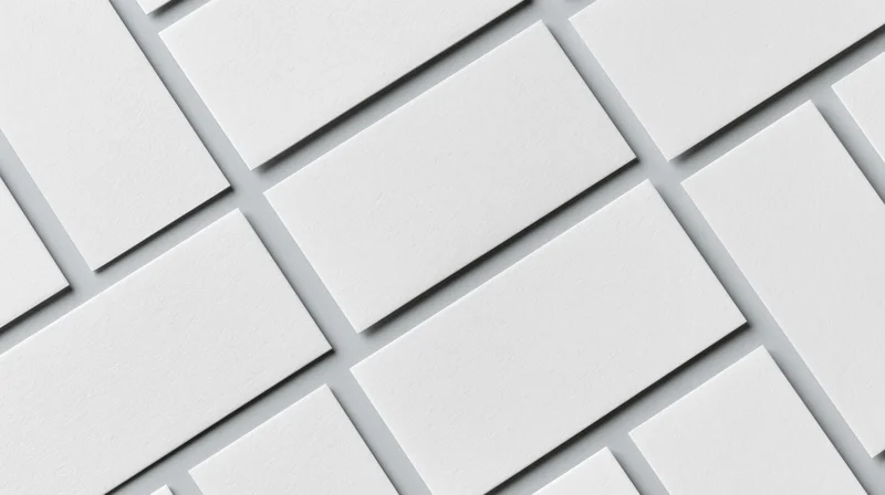 Blank white business cards arranged diagonally in a repeating pattern on a flat surface