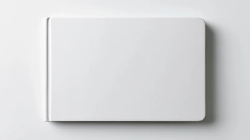 Blank white hardcover book lying flat on white surface viewed from above