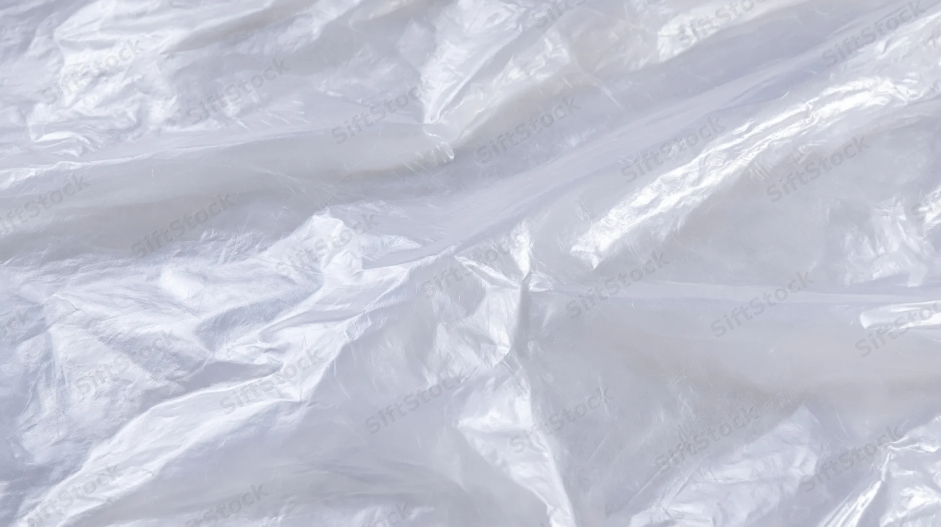 Crumpled transparent plastic bag surface with folds and creases on white background