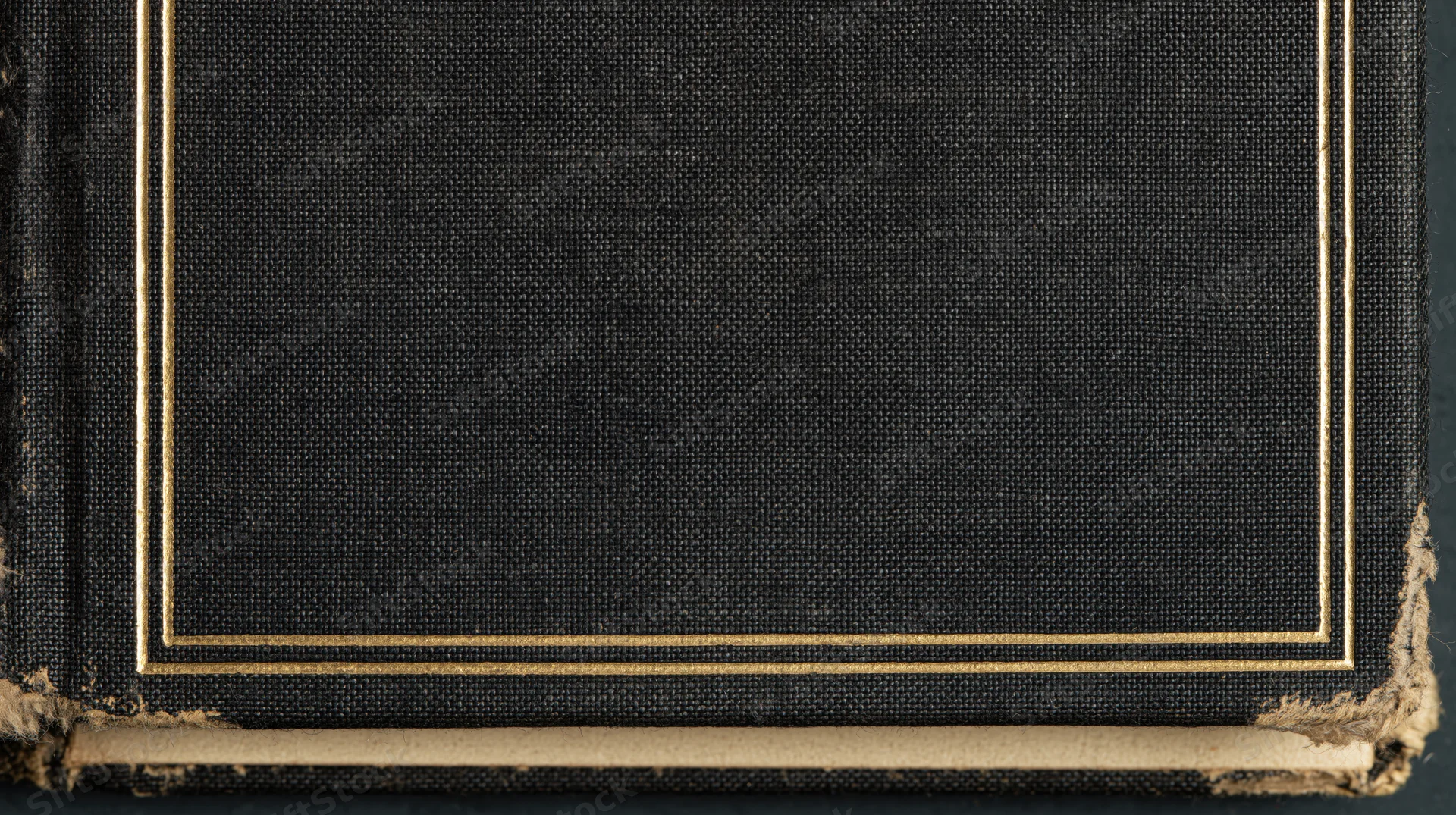 Close-up of an antique hardcover book cover with gold trim and worn edges