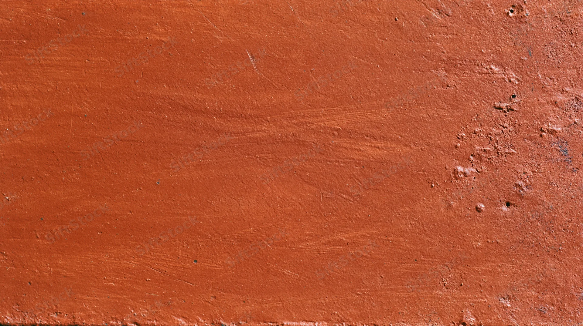 Close-up of a worn reddish-brown painted metal surface with rust and scratches