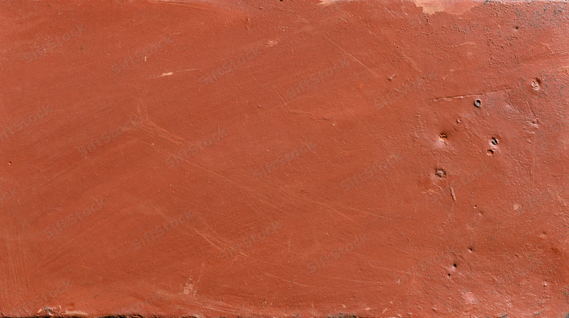 Close-up of a worn reddish-brown painted metal surface with scratches and dents