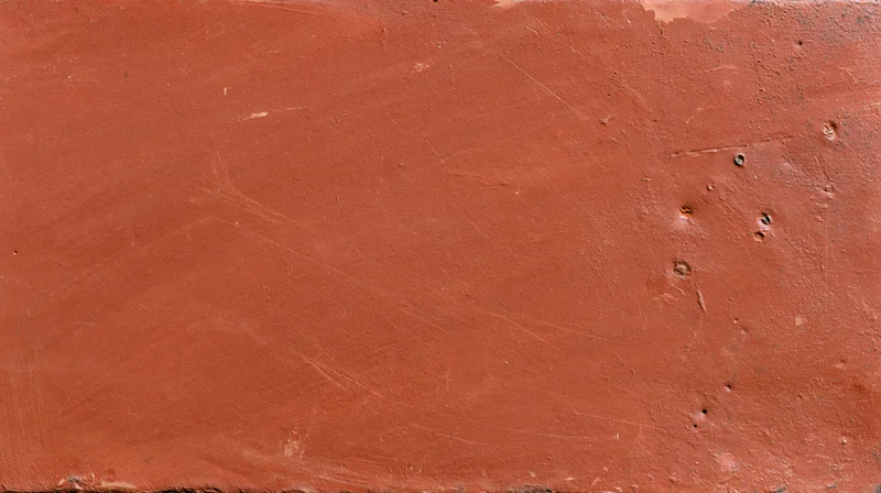 Close-up of a worn reddish-brown painted metal surface with scratches and dents