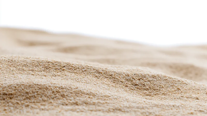 Close-up of dry beach sand with wind-formed ripples on a white background