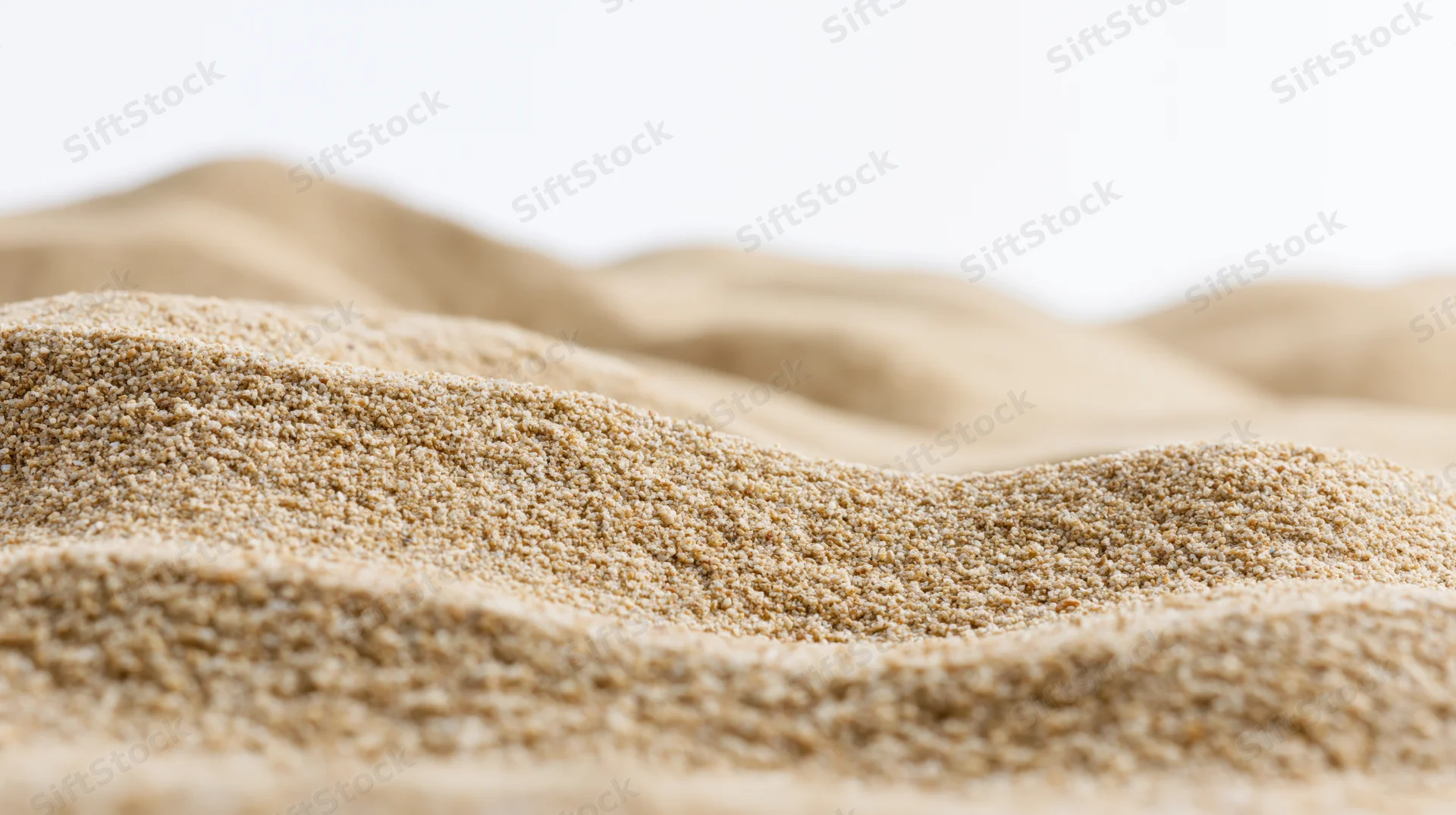 Close-up of dry beach sand forming undulating ripples against a white background