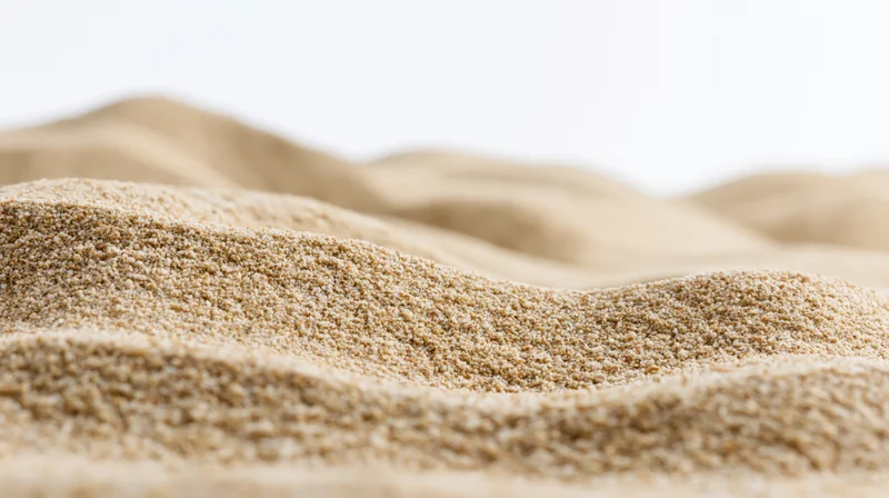 Close-up of dry beach sand forming undulating ripples against a white background