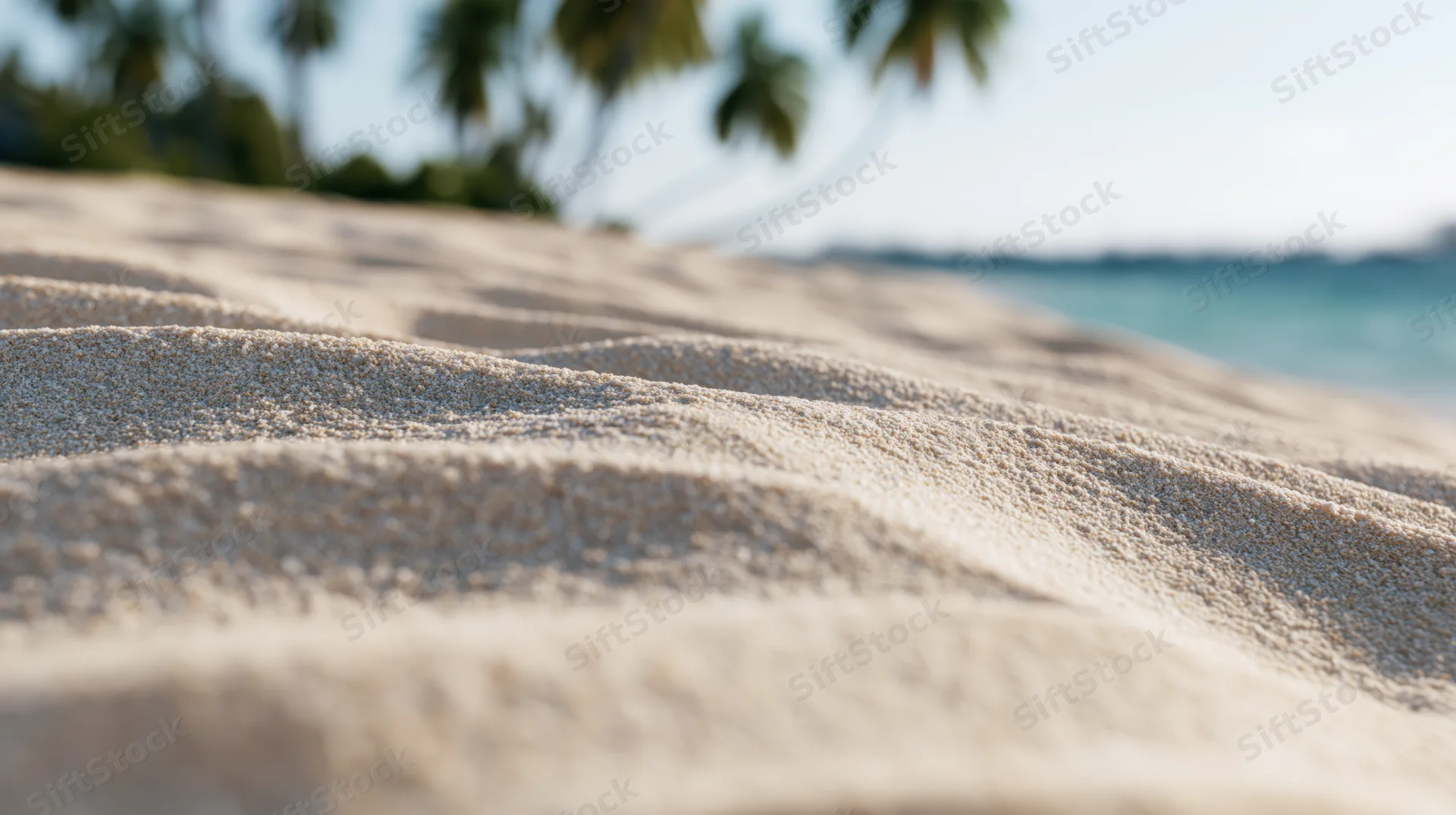 Closeup of smooth white sand dunes on a tropical beach with palm trees and ocean in the background