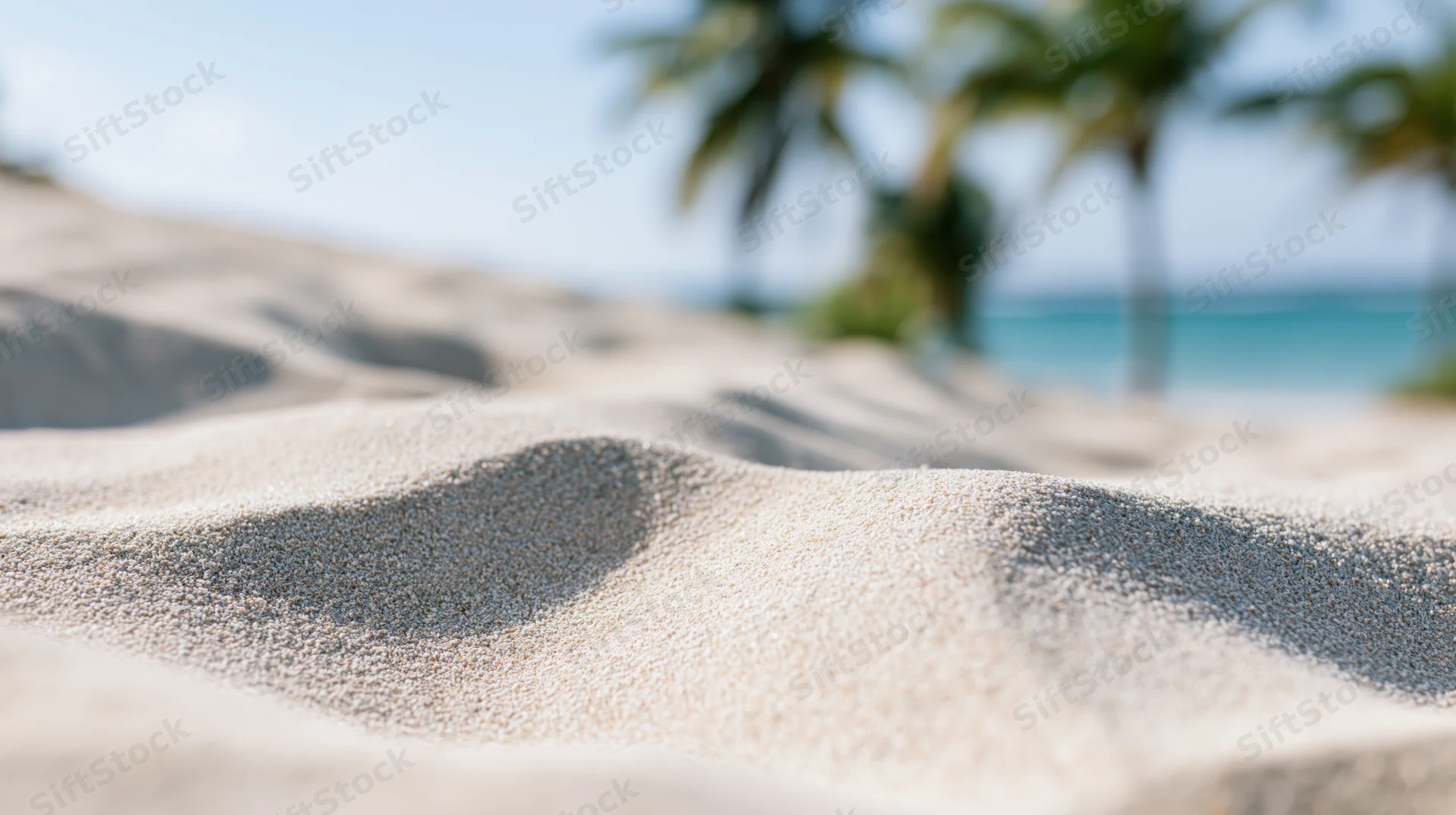 Closeup of smooth white sand dunes on a tropical beach with palm trees and ocean in the background