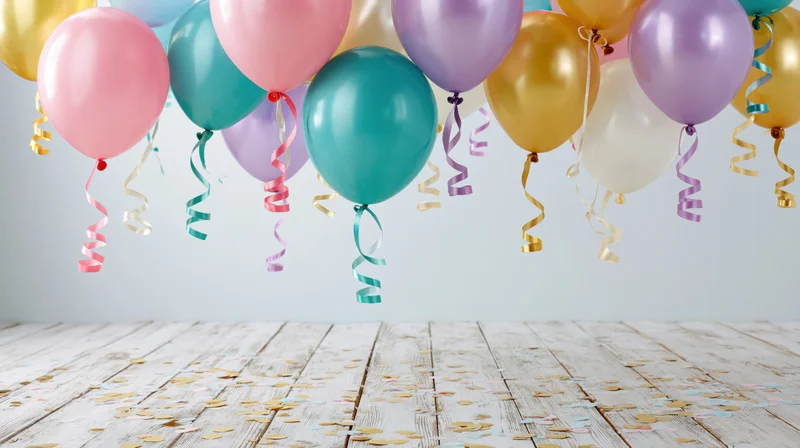Colorful helium balloons floating above a wooden floor scattered with confetti