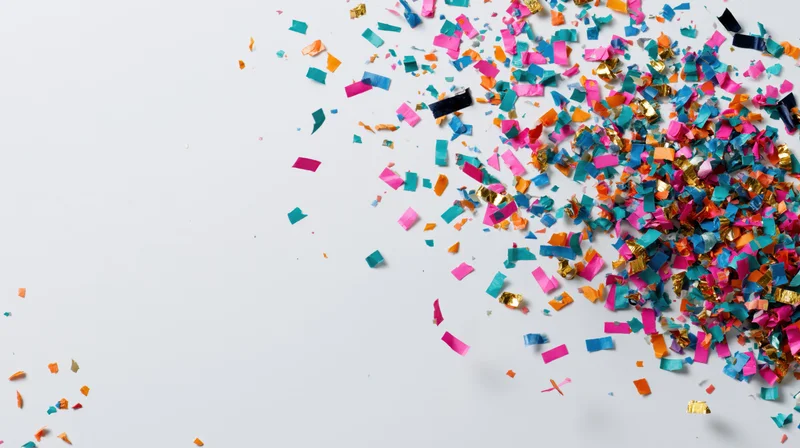 Colorful paper confetti scattered across a white surface with copyspace on the left