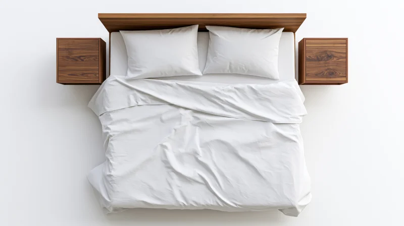 Overhead view of a double bed with white cotton bedding and two pillows, flanked by wooden nightstands against a white background