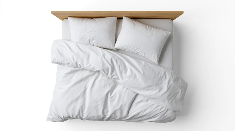Double bed with white cotton duvet and two pillows viewed from above on white background