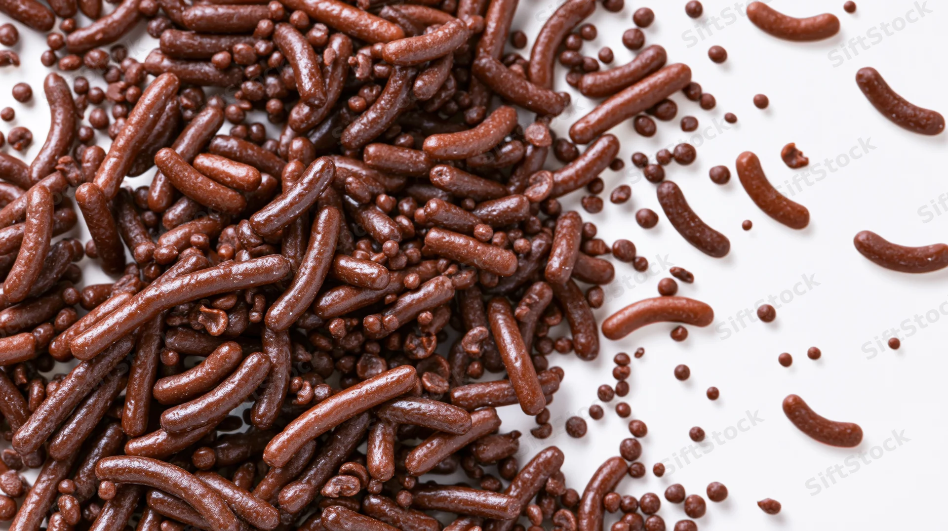 Chocolate sprinkles scattered in a pile on white background with copyspace