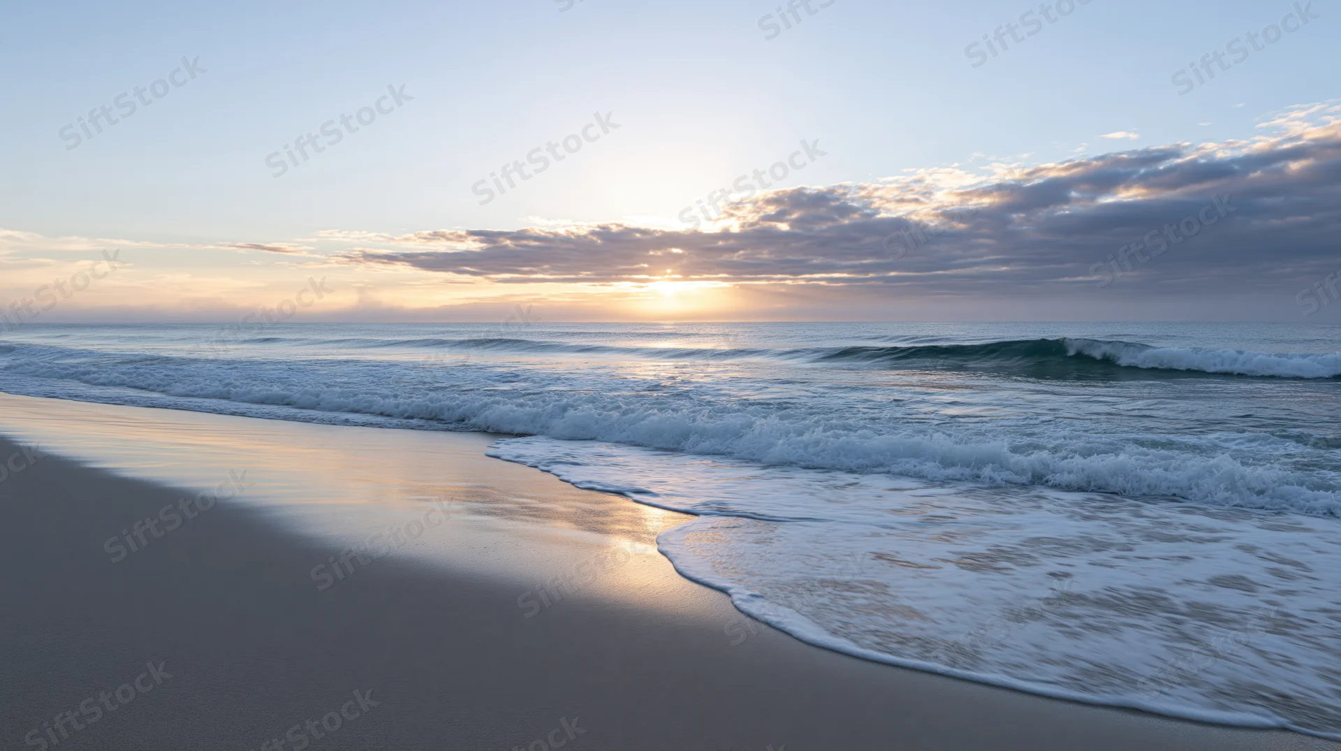 Gentle waves washing onto a sandy beach at sunrise with soft light reflecting on wet sand and sky