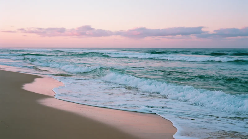 Gentle waves rolling onto a sandy beach at sunset