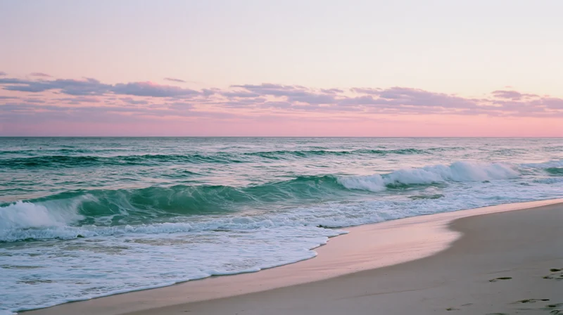 Gentle waves rolling onto a sandy beach at sunset