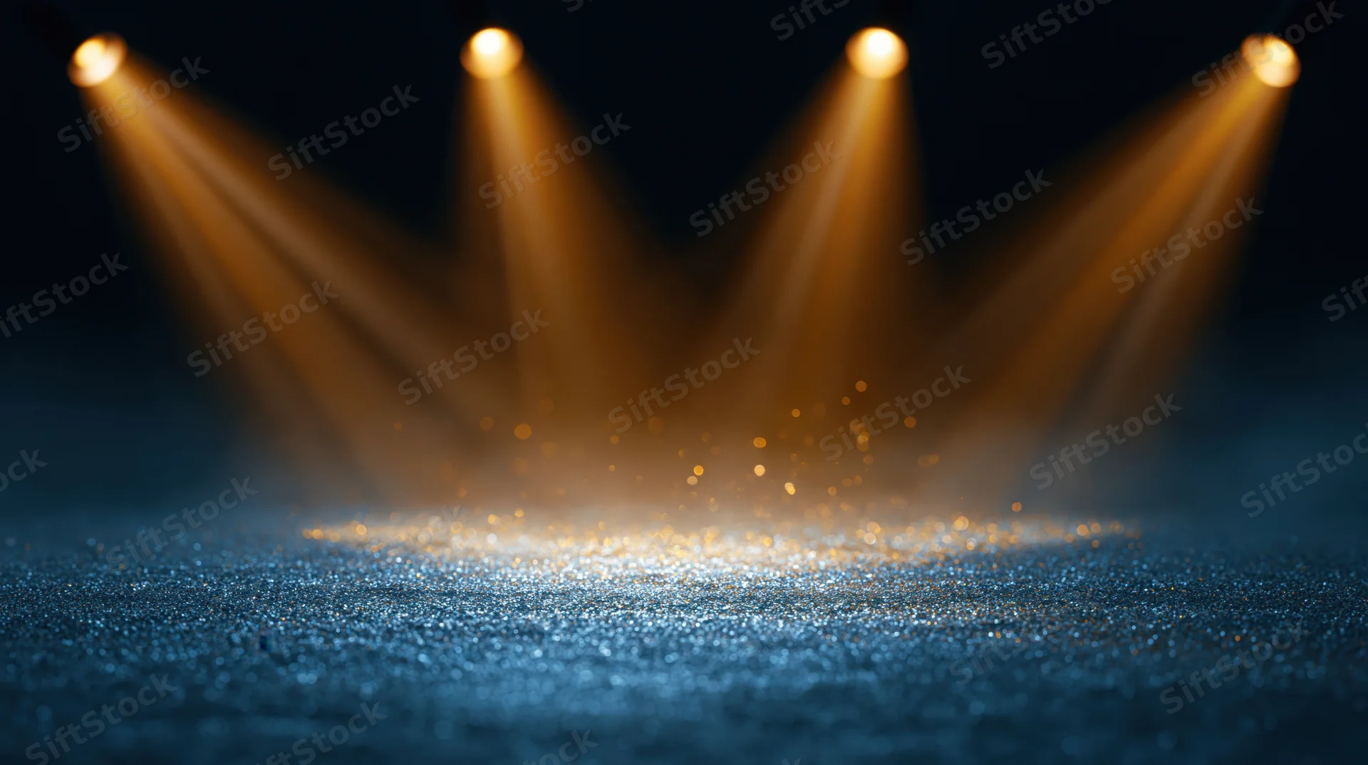 Stage floor covered in blue glitter under golden spotlights