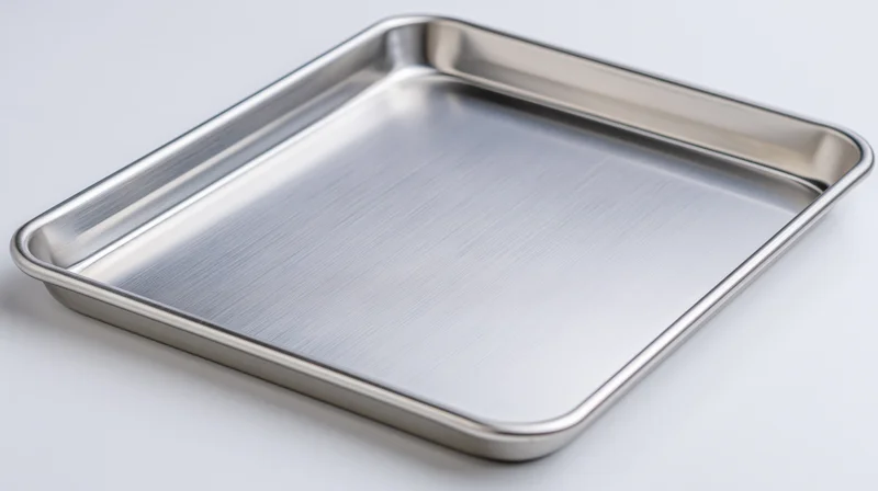 Empty stainless steel baking sheet on plain white background