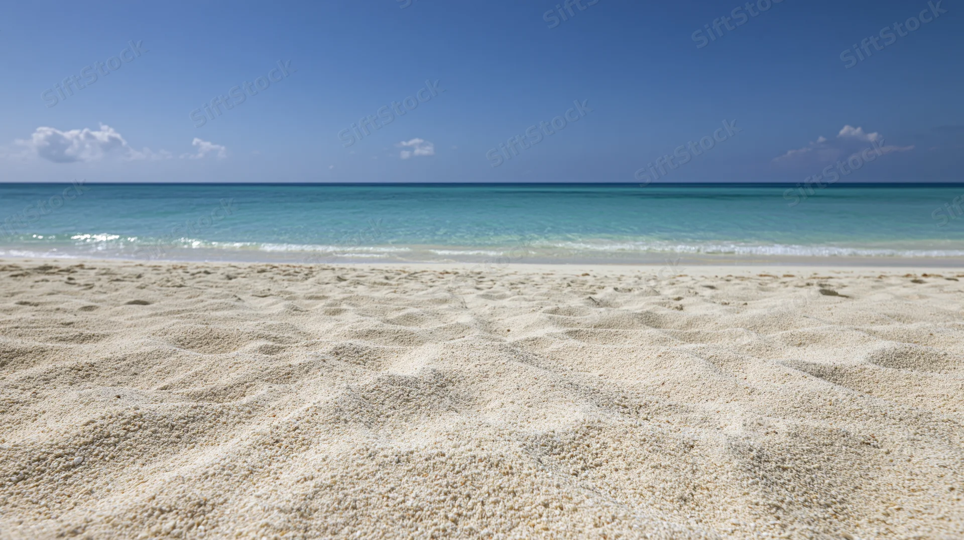 Empty tropical beach with fine white sand in foreground and turquoise ocean under clear blue sky