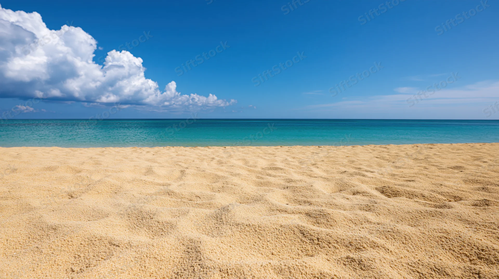 Empty tropical beach with fine golden sand under clear blue sky and turquoise ocean