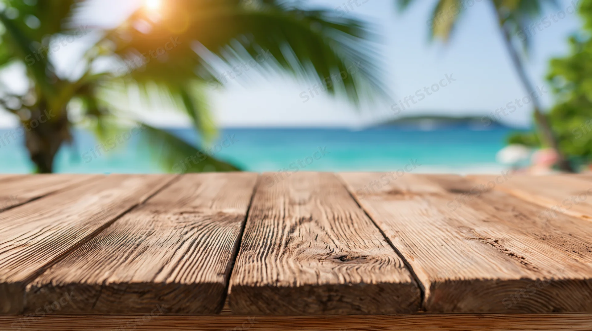 Wooden table surface in foreground with tropical beach and palm trees in background