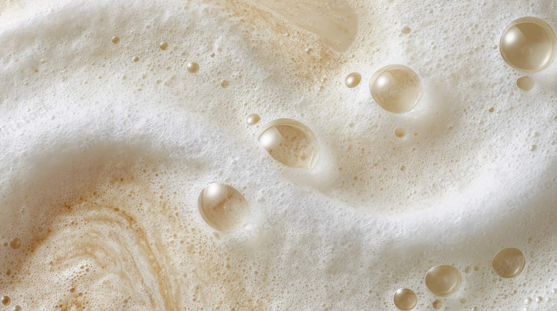 Creamy white foam surface with bubbles and swirls from a carbonated beverage