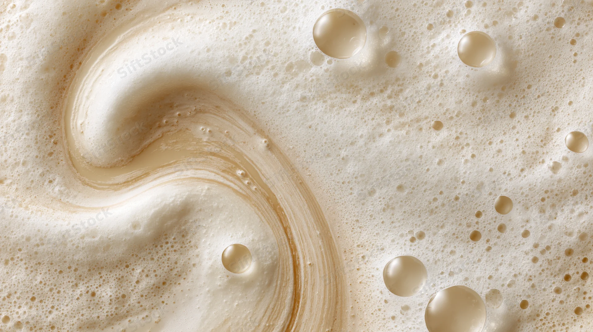 Creamy foam surface with swirling pattern and bubbles, close-up view