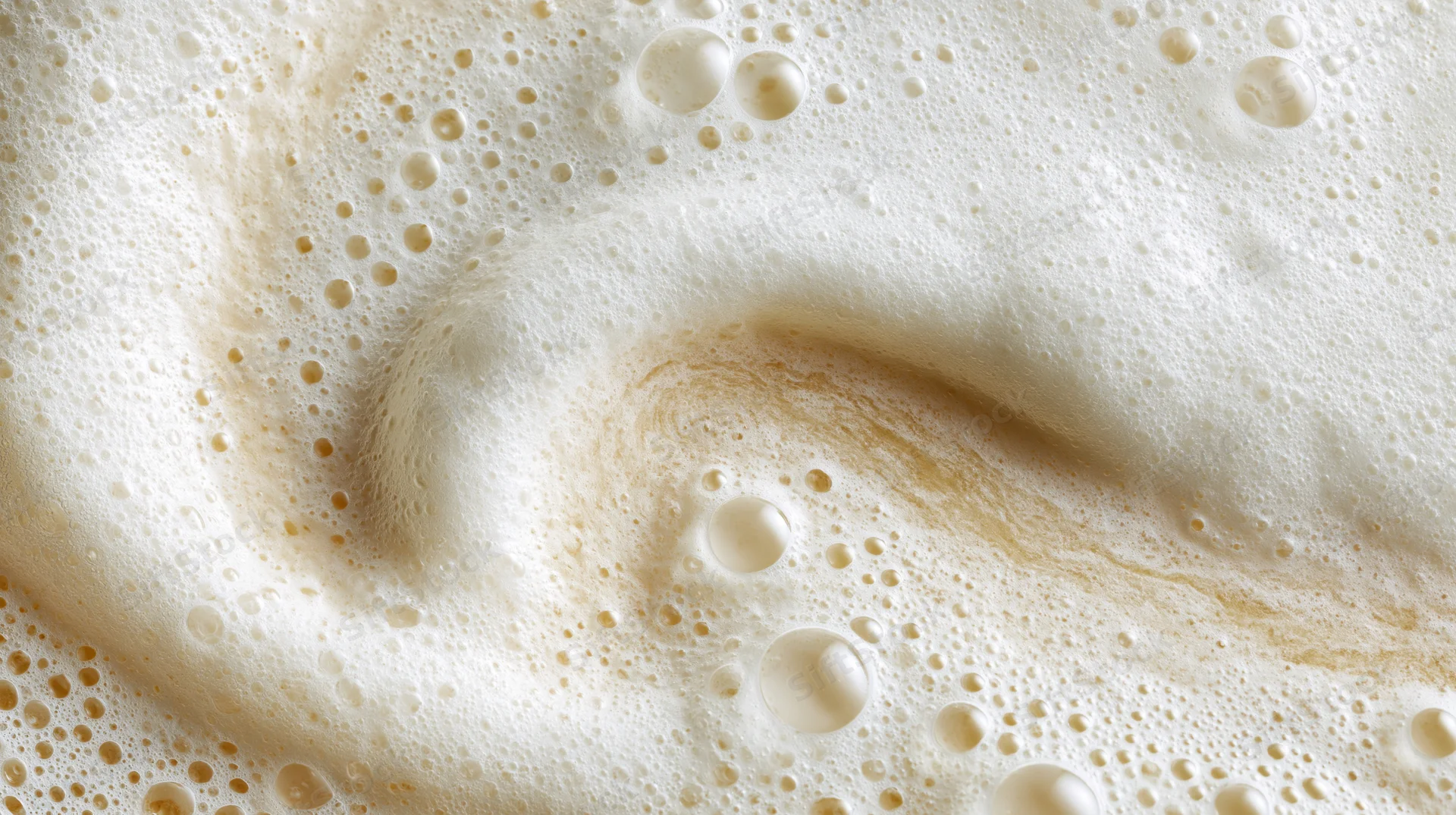 Creamy foam surface with swirling bubbles and golden highlights