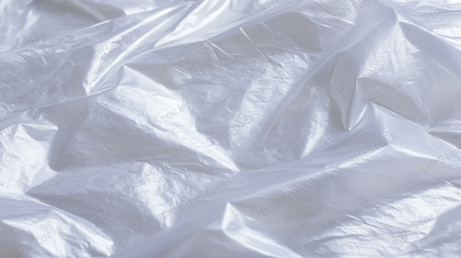 Crumpled clear plastic poly bag lying flat on white surface
