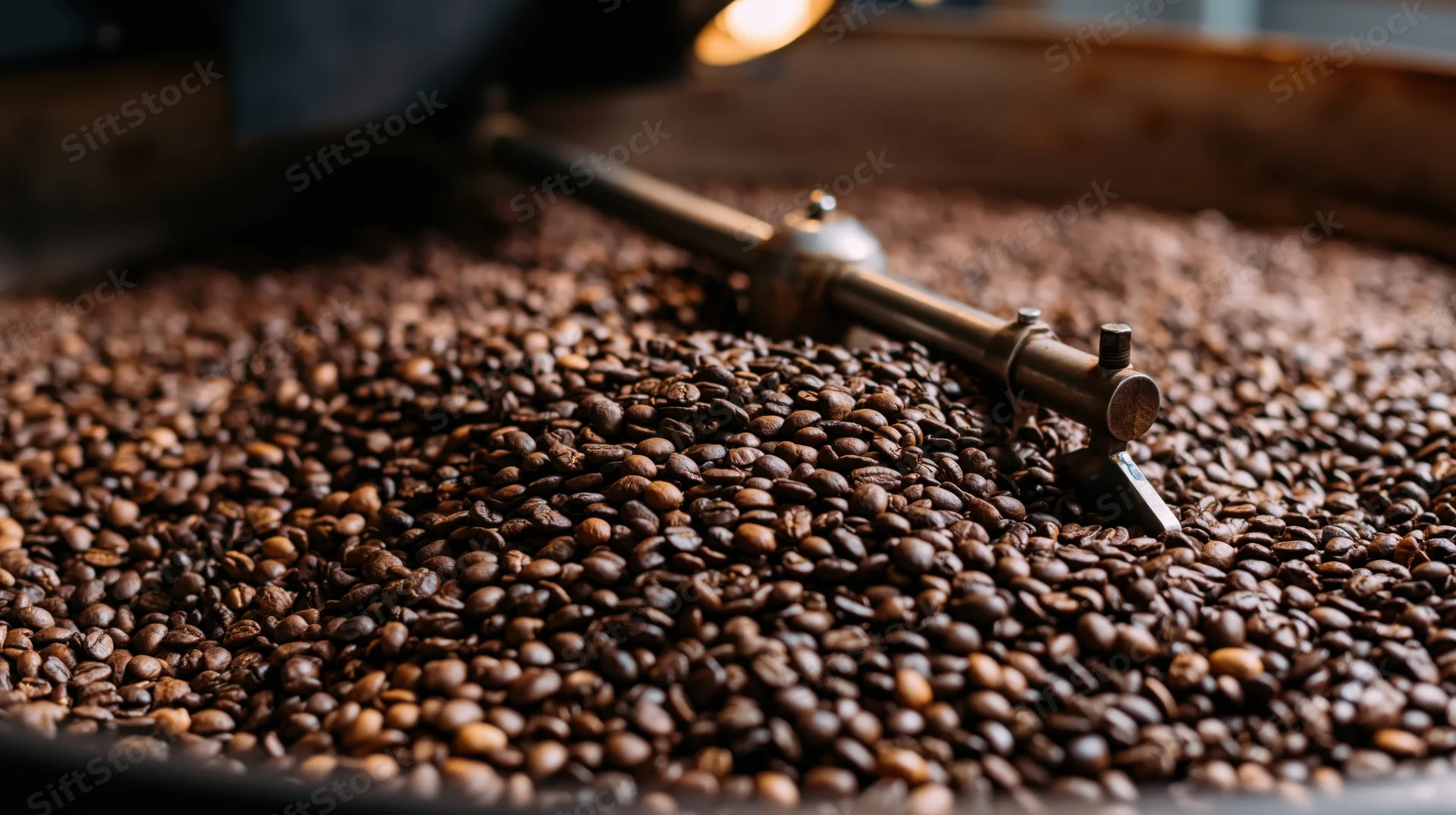 Roasted coffee beans spread across a large cooling tray in a roasting facility