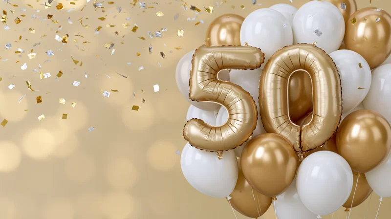 Gold foil number 50 balloons with white and gold latex balloons and falling confetti against a soft golden bokeh background