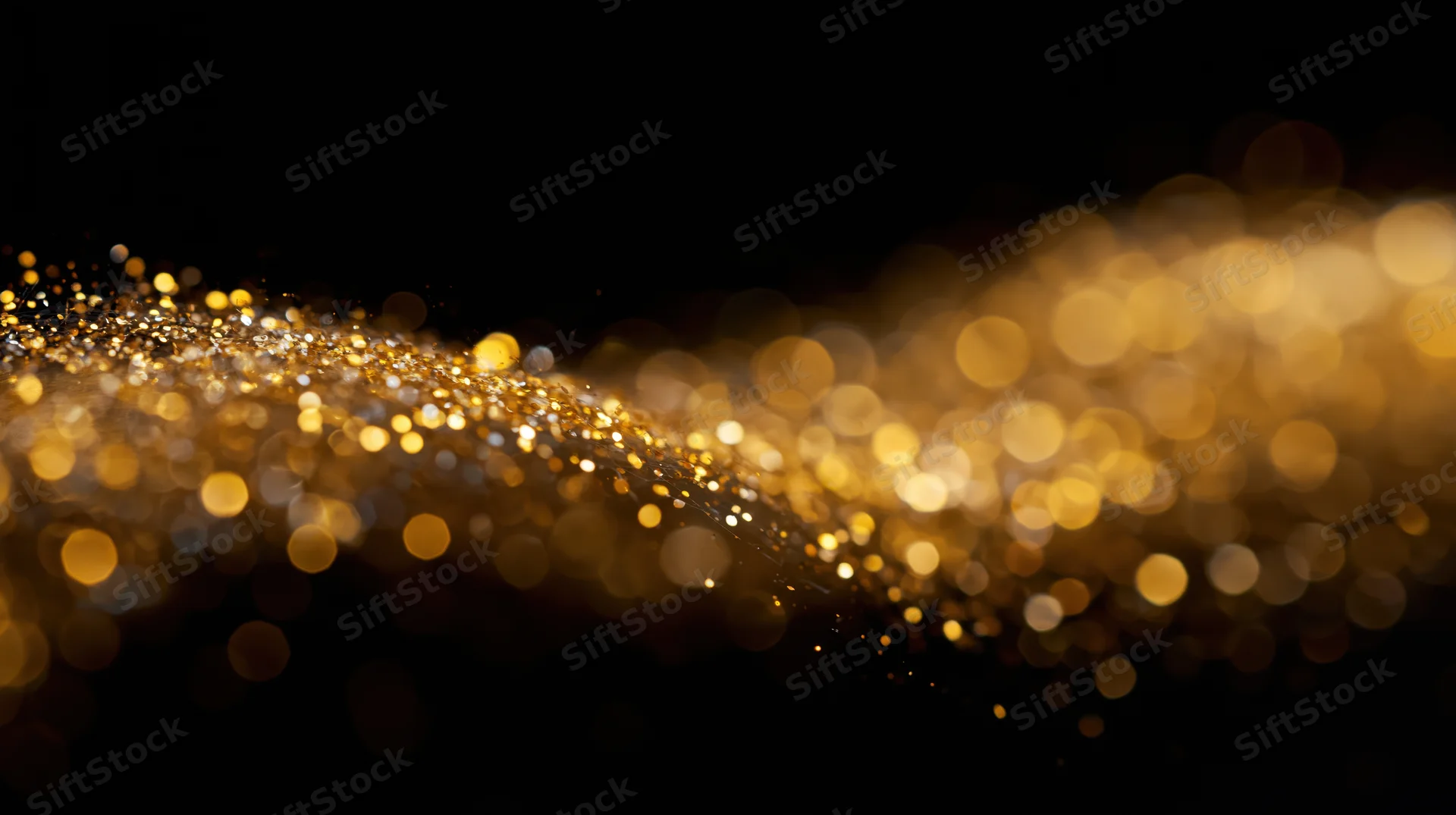 Golden glitter particles drifting in a diagonal wave across a dark background