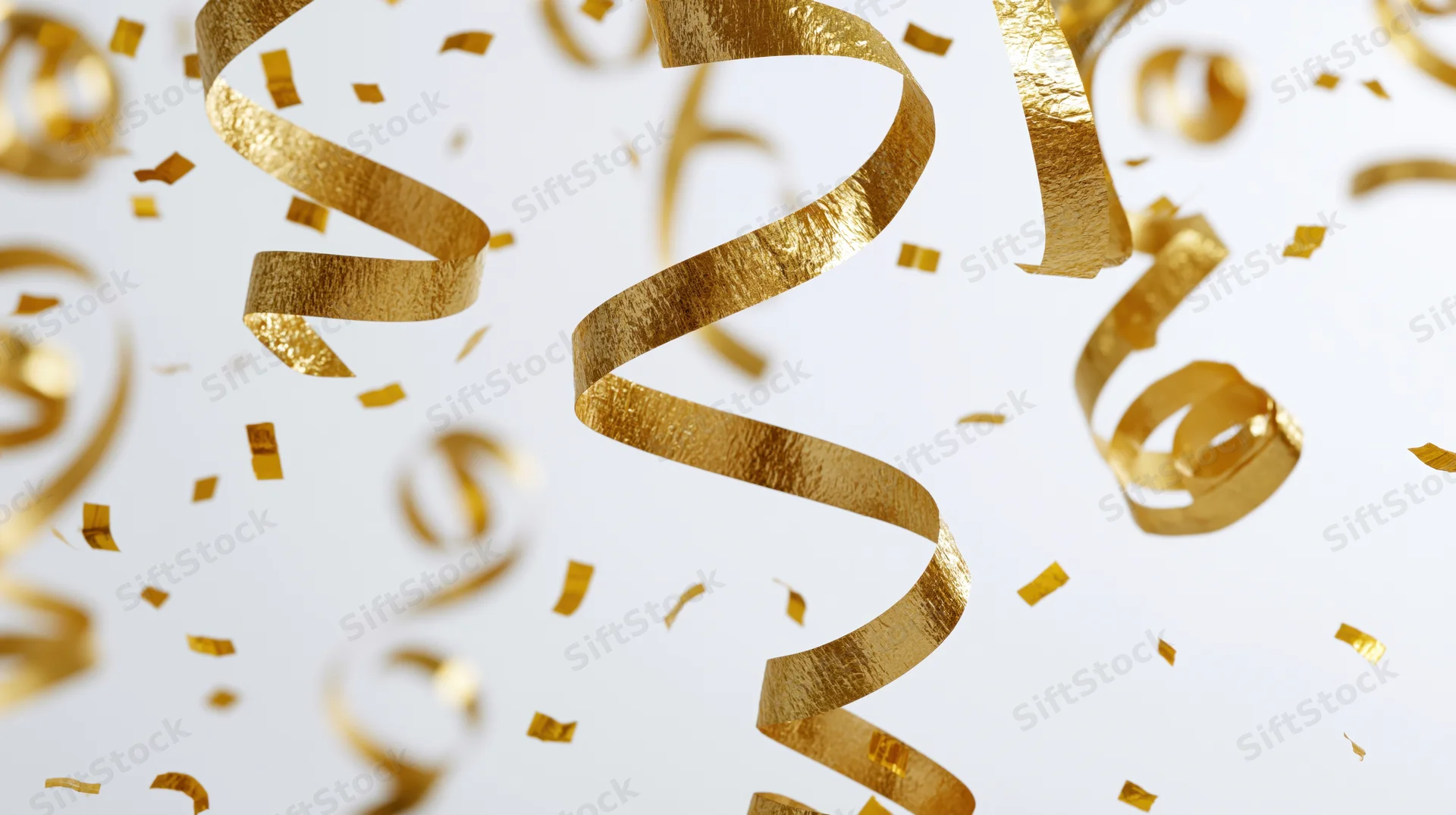 Golden metallic streamers and confetti pieces falling and twisting in midair against a white background