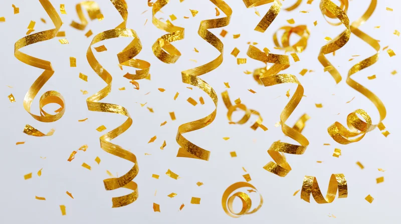 Golden metallic streamers and confetti pieces falling in mid-air against a white background